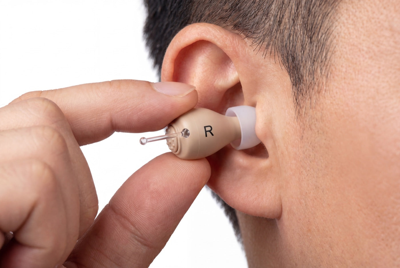 A person placing the right hearo hearing aid into their ear canal